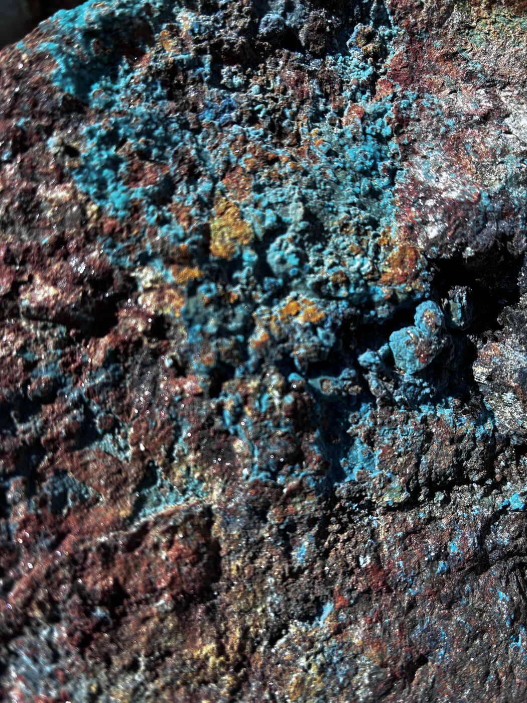 Detalle de roca con mineralización de cobre oxidado: crisocola y óxidos sobre matriz ferruginosa